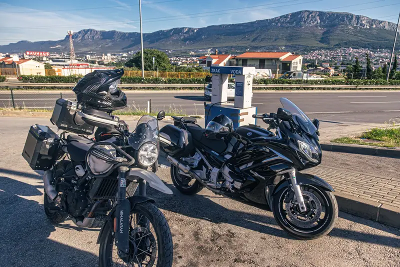 Dva motora na benzinskoj postaji, planina u pozadini