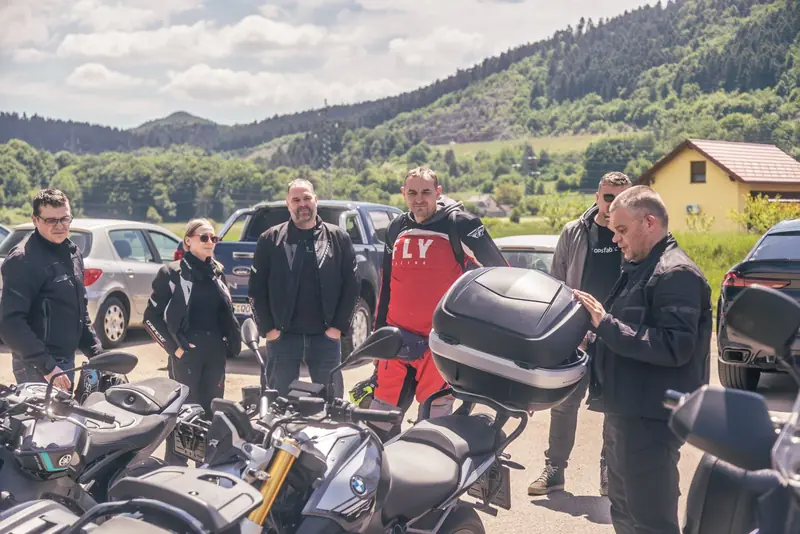 Grupa motorista razgovara uz motore, brda u pozadini